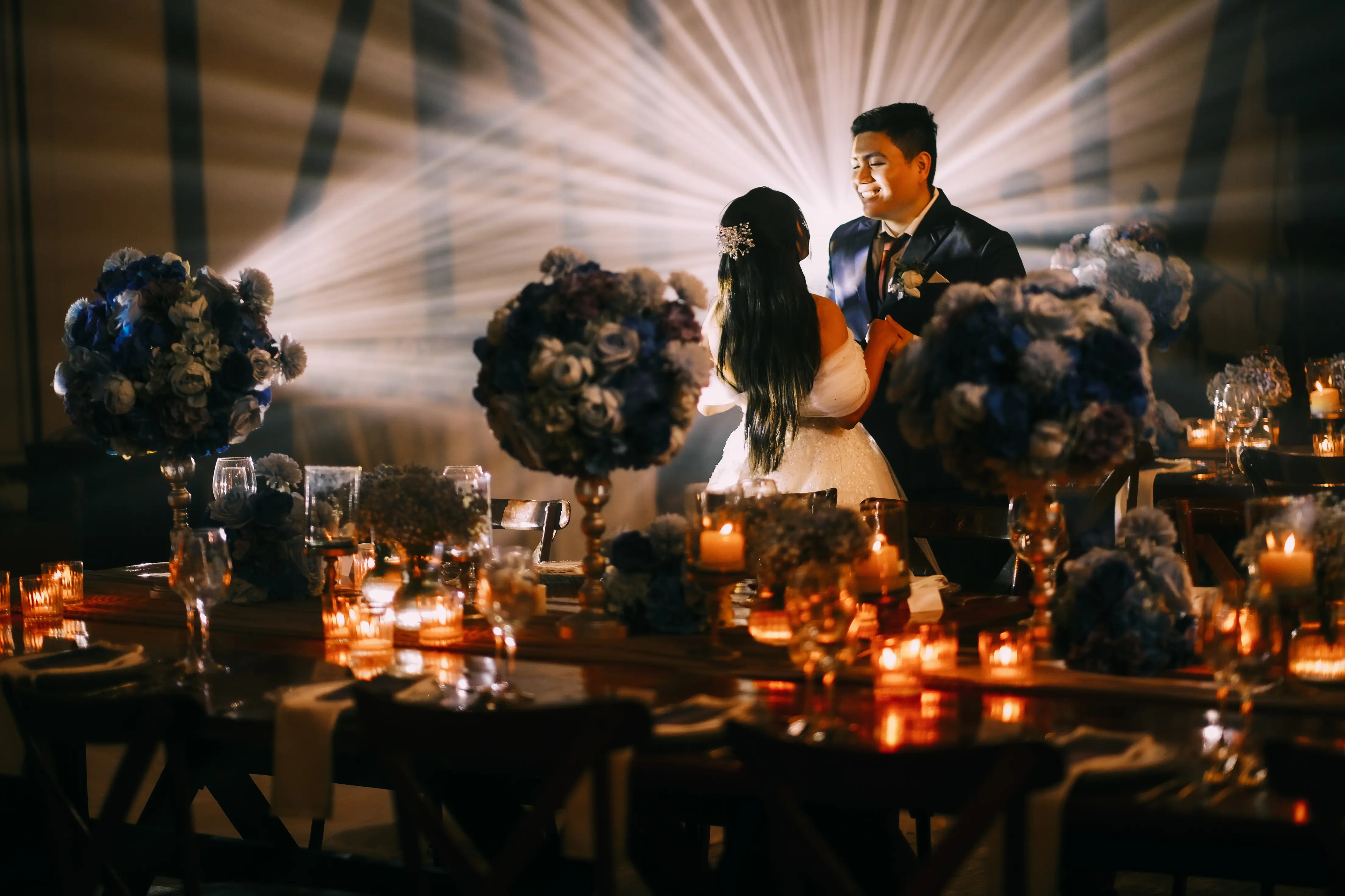 fran and luisa photo holding hands face to face with a background of reception's table setup